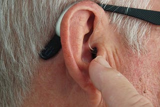 A close-up picture of a man’s ear with his finger touching it