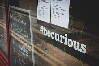 Store window with the hashtag “be curious” on the window