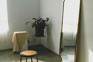 A long mirror with a small stool in front.