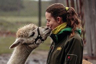 A woman kissing a lama.