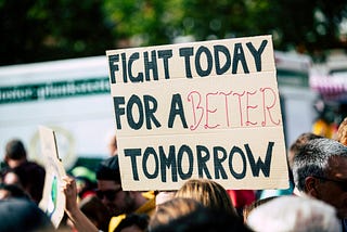 Poster held up over the heads of demonstrators. It reads ‘Fight today for a better tomorrow’