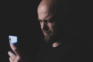 A Man frowning while looking at his cell phone