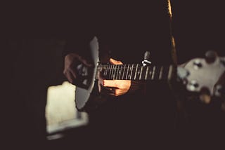 A musician playing a banjo, close up.