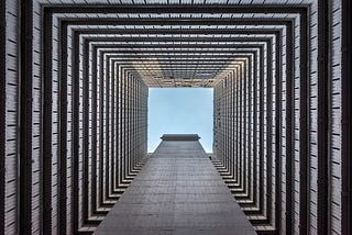 looking upwards to an open sky from the ground floor of a building