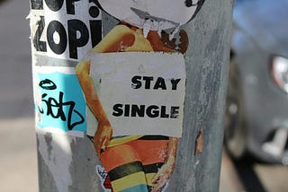 sticker on a lamp post that says ‘stay single’