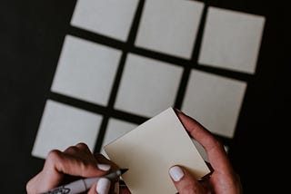 A person’s hands laying sticky notes in a grid.