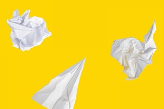 Paper planes and crumbled paper on a gross yellow background