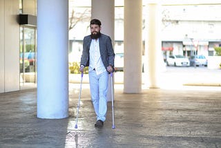 Man with neuromuscular disorder using walking sticks outdoors — Invitae genetic testing blog