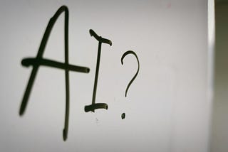 A whiteboard with ‘AI?’ weitten on it in black.