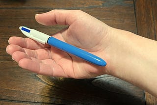 An open hand holds a pen in its palm.