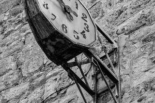 A black and white image of an old clock attached to a stone wall