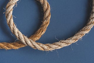 A length of hemp rope laid out on a blue background, with one section shown as a loop.