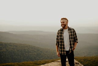 Picture showing a man happy on the cliff of a mountain.