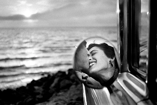 Elliott Erwitt’s photo of 1950’s rear mirror showing couple kissing.