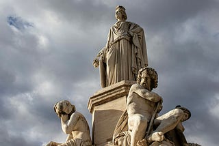 A group of ancient statues with a statue of a goddess at the top