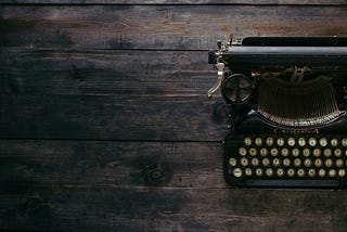 Old typewriter sitting on top of a wooden desk.