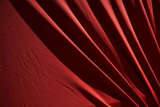 A close-up of red fabric displaying soft folds and shadows