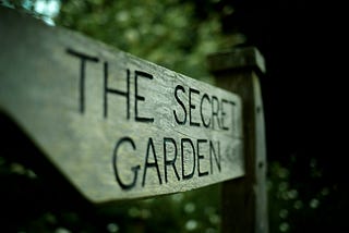 A wooden signpost, carved with the words “the secret garden”