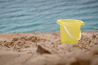 A yellow bucket on a sandy beach