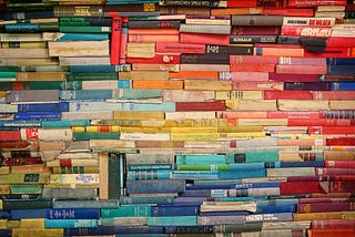 A pile of old colourful books staked ontop of one another.