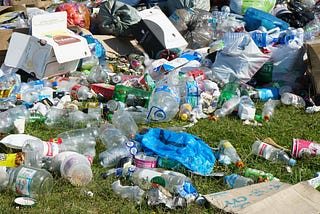 plastic bottles and other plastic waste items overflowing onto the ground.