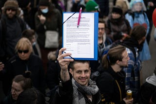 Man in crowd holding up paper