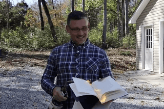 Pastor Greg Locke holding a book and lighting it on fire