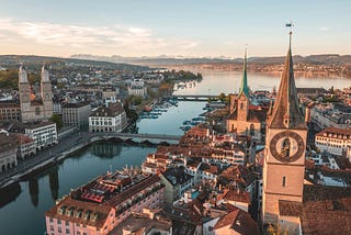 A beautiful view of a city consisting of churches, buildings, and a river running through the center of the landscape