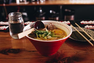 A table with a warm bowl of soup setting on it.