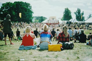 Three women sitting slightly apart from a larger group, symbolizing isolation within a shared space.