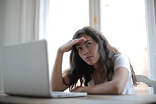 An exasperated woman sitting at a computer.