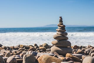 A picture of rocks on a beach with a rock monument in the middle