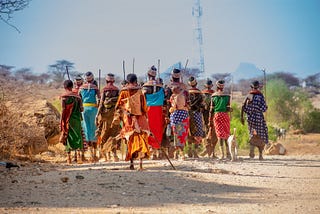 Photo Description: A group of Indigenous women from the Samburu Tribe in Kenya walking along a road in colorful clothes.