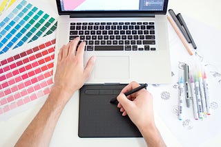 A designer working on a project with a laptop, stylus and colour swatches.