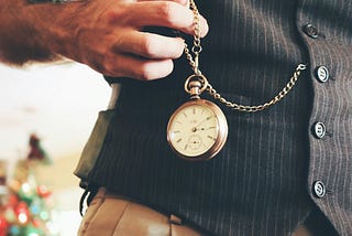 A man wearing a waistcoat and holding a pocket watch.