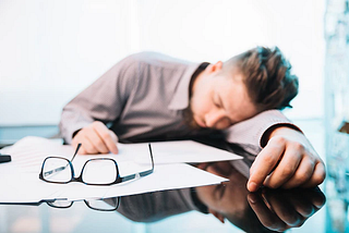 A man sleeping during his working hours on his desk.