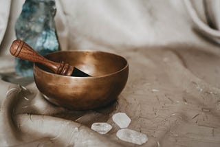 Bronze sound bowl pictured with three clear quarts crystal sitting right next to it.