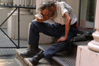 older man on the steps, holding his head in his hands, possibly crying