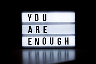 Illuminated sign with the words ‘you are enough’ written