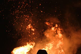 silhouette of a person looking at a large fire