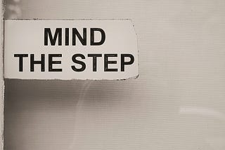 A sign warning to ‘Mind the Step’ indicating a potential tripping hazard or change in floor level ahead.