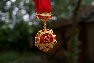 Photo of bright gold and red medal with communist hammer and sickle.