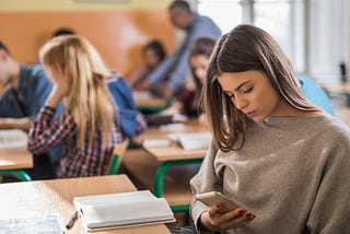 teenager looking at their phone in class