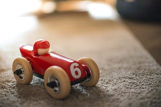 A wooden toy race car and driver.