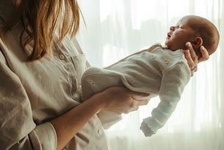 An partial view of a woman holding a newborn baby in her hands.