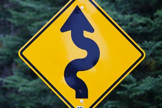 A yellow diamond-shaped sign with a wiggling arrow on it pointing up.