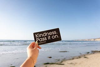 Kindness. Pass it on. Beach background.