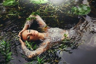A woman floating in a lake surrounded by vegetation.