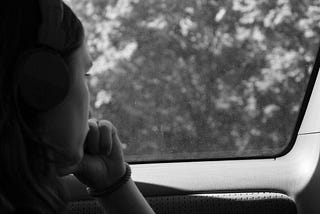 Black and white picture of teen staring out car window, profile angle.