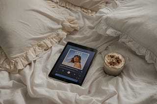 Tablet device playing music with a coffee on the bed